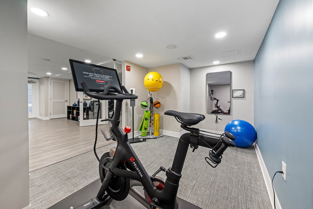 a gym with exercise bikes and a yellow ball on the wall