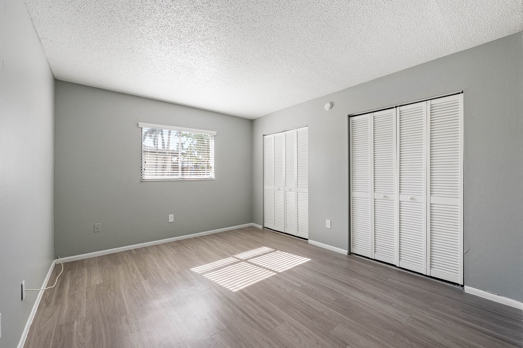 an empty living room with wood flooring and a window