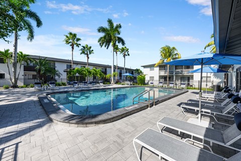 a swimming pool with chairs and umbrellas in front of a building