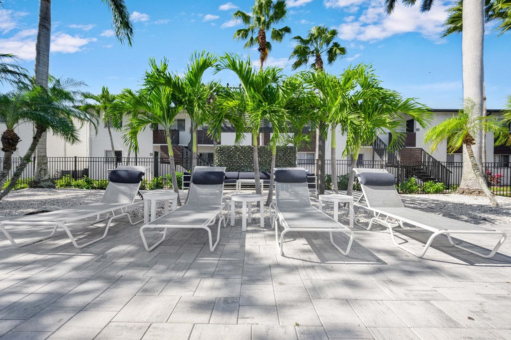 a patio with white chairs and palm trees