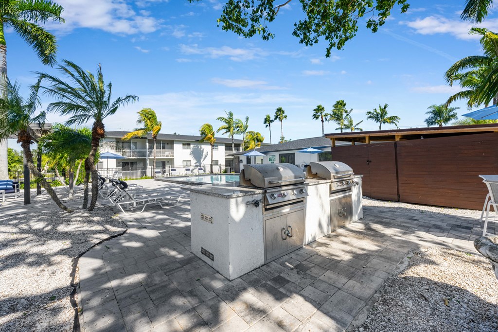 a patio with two grills and palm trees