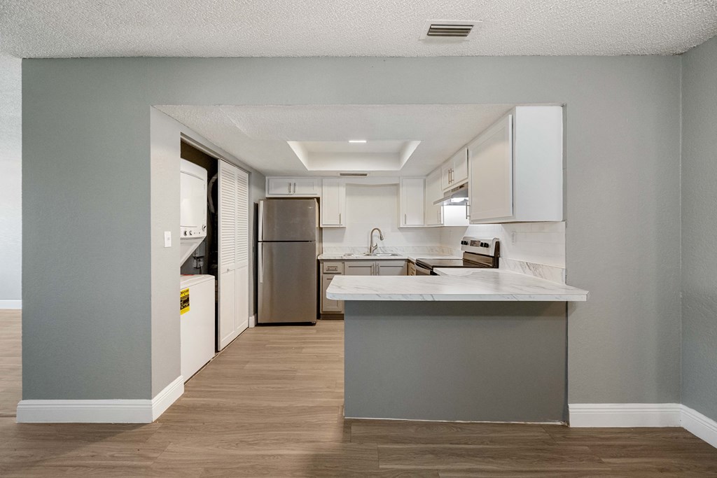 a renovated kitchen with white cabinets and stainless steel appliances