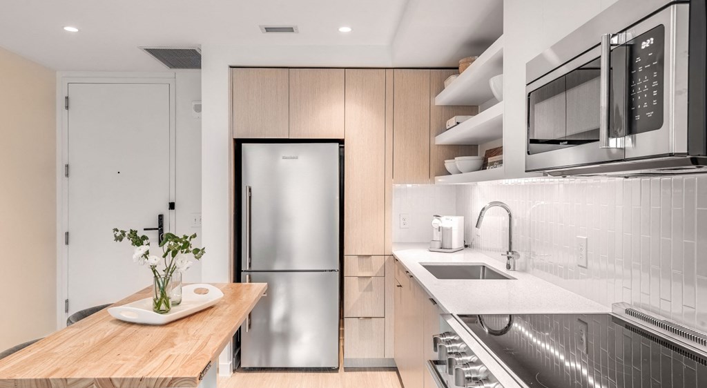 A modern kitchen with a wooden table and stainless steel appliances.