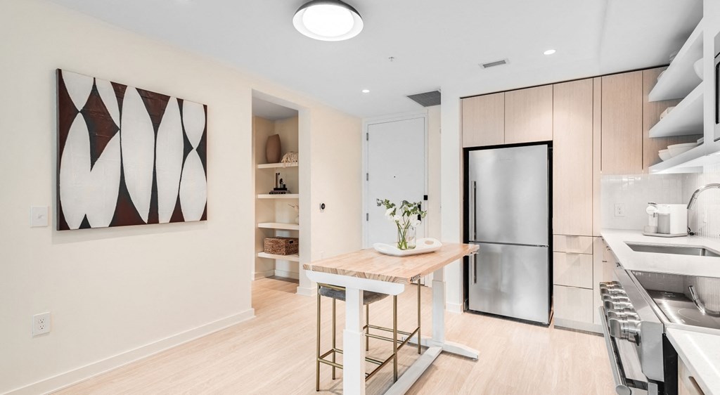 A modern kitchen with a wooden table and stainless steel appliances.
