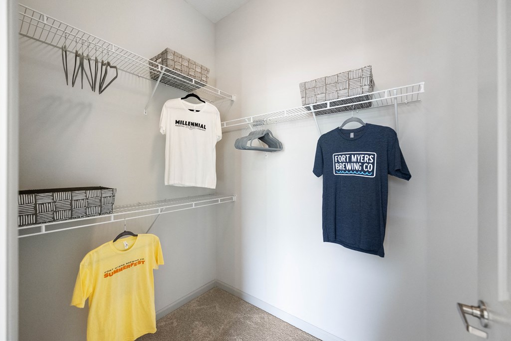 a walk in closet with shirts hanging on a rack and a shirt on the wall