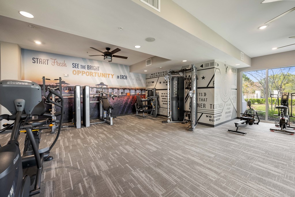a gym with weights and cardio machines and a wall with a mural of the gym