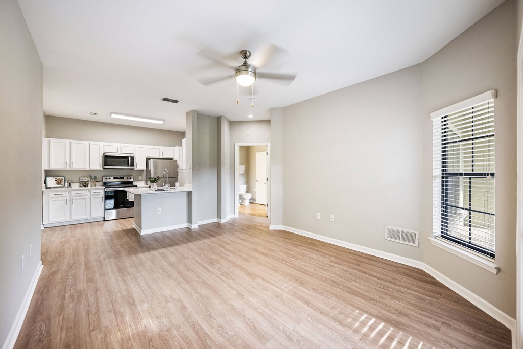 an empty living room and kitchen with a ceiling fan