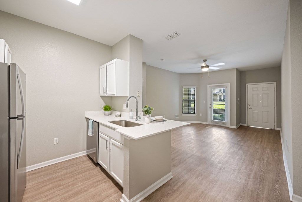 an empty kitchen and living room with a refrigerator and a sink