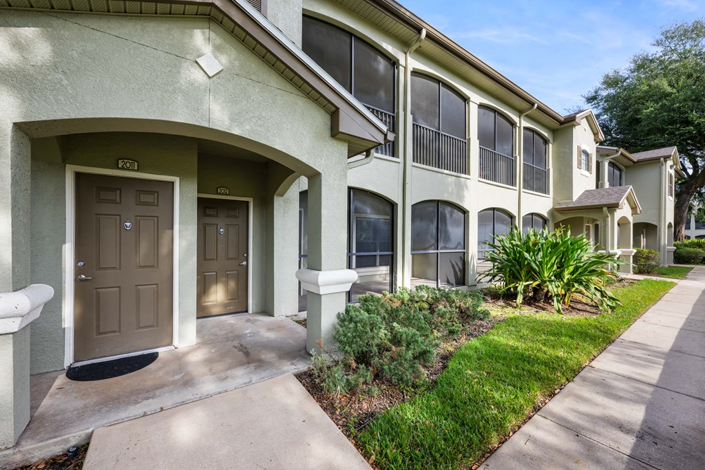 a sidewalk in front of a building with a brown door
