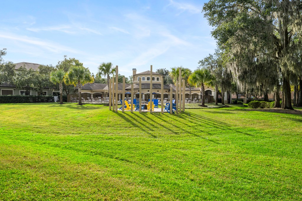 a large lawn with a playground and a mansion in the background
