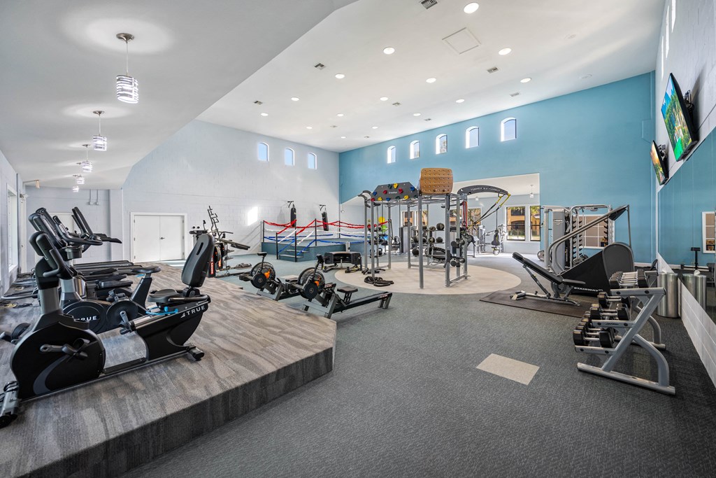 a gym with cardio equipment and weights on a wooden floor