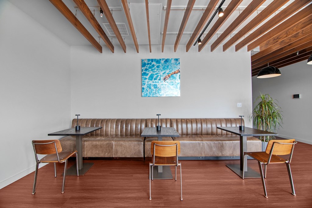 a lounge area with a couch and tables and a painting on the wall