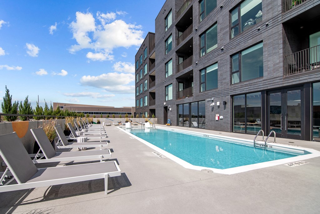 a swimming pool in front of a building with lounge chairs