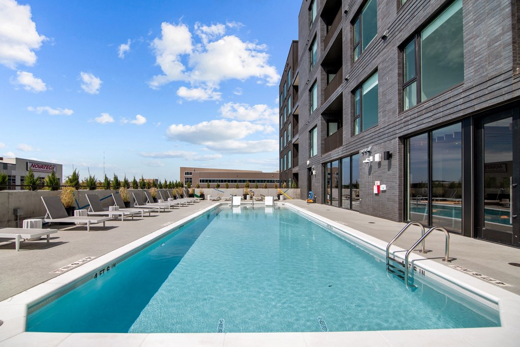 a swimming pool in front of a building with a blue sky
