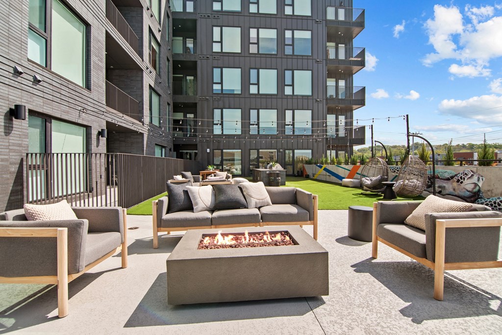 a patio with couches and chairs around a fire pit