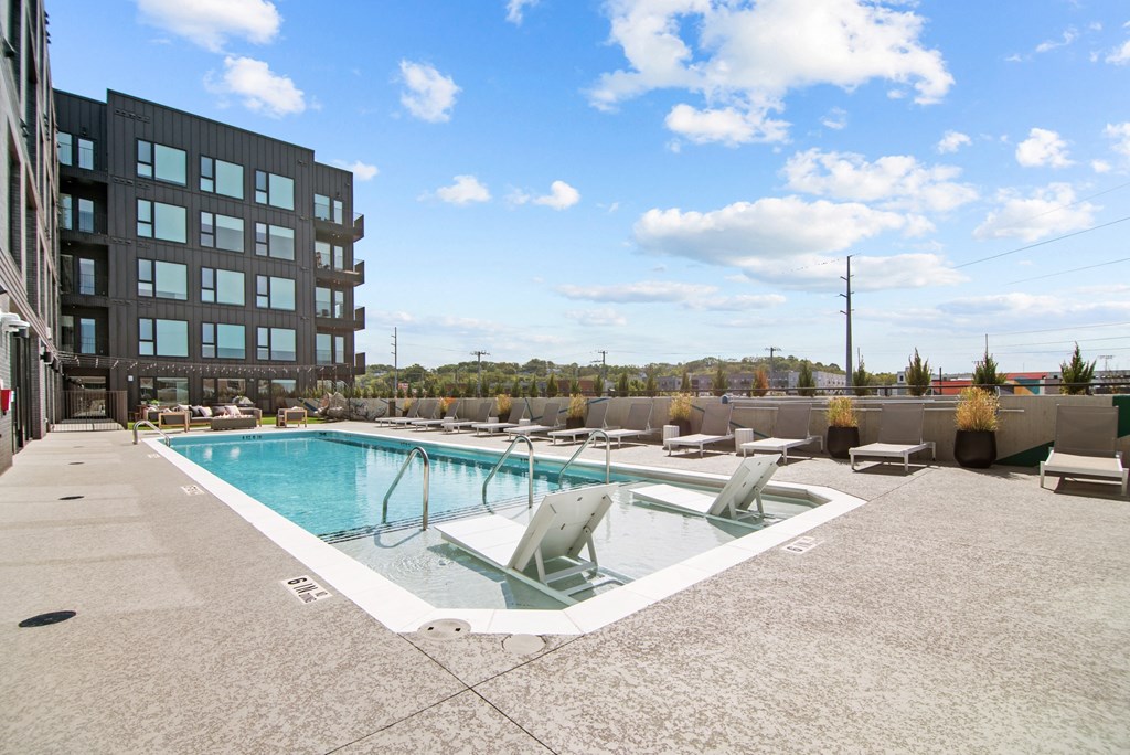 a pool with chairs and a building in the background