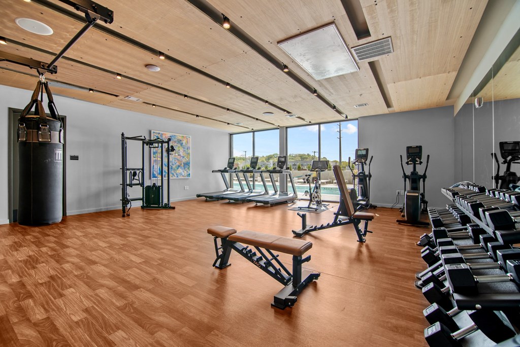 a gym with cardio machines and weights on a wooden floor