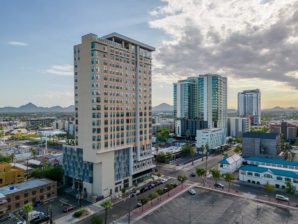 A tall building with many windows is in the foreground of a cityscape.