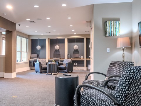 a lounge area with chairs and tables and a tv