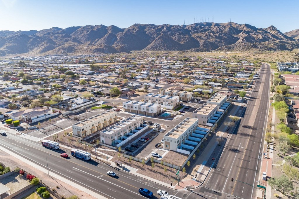 A city street with cars and buildings with a mountain in the background.