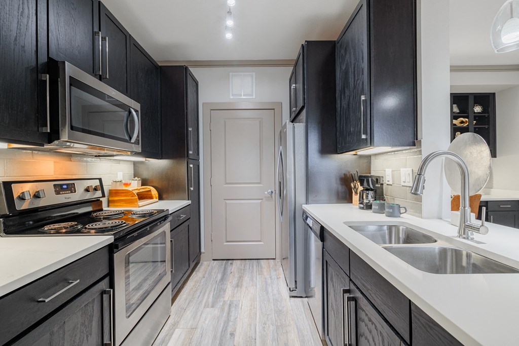 a kitchen with black cabinets and white counter tops and a sink