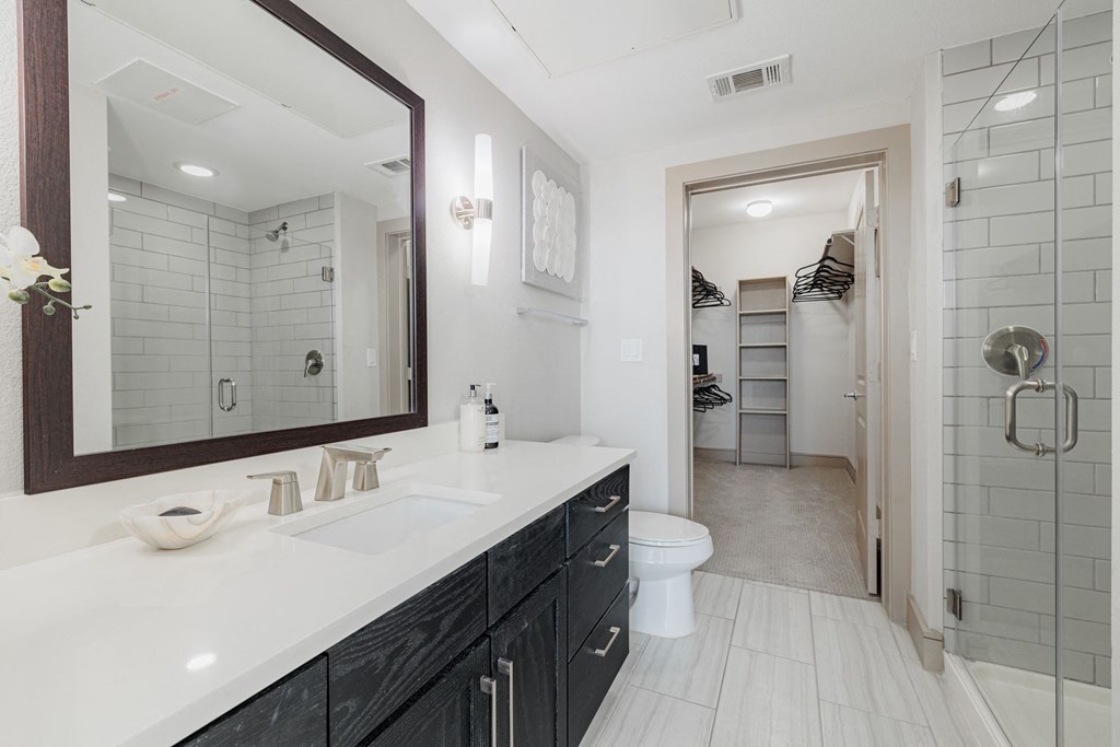 a white bathroom with a large mirror and a toilet