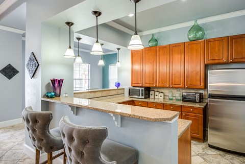 A kitchen with a counter and chairs.