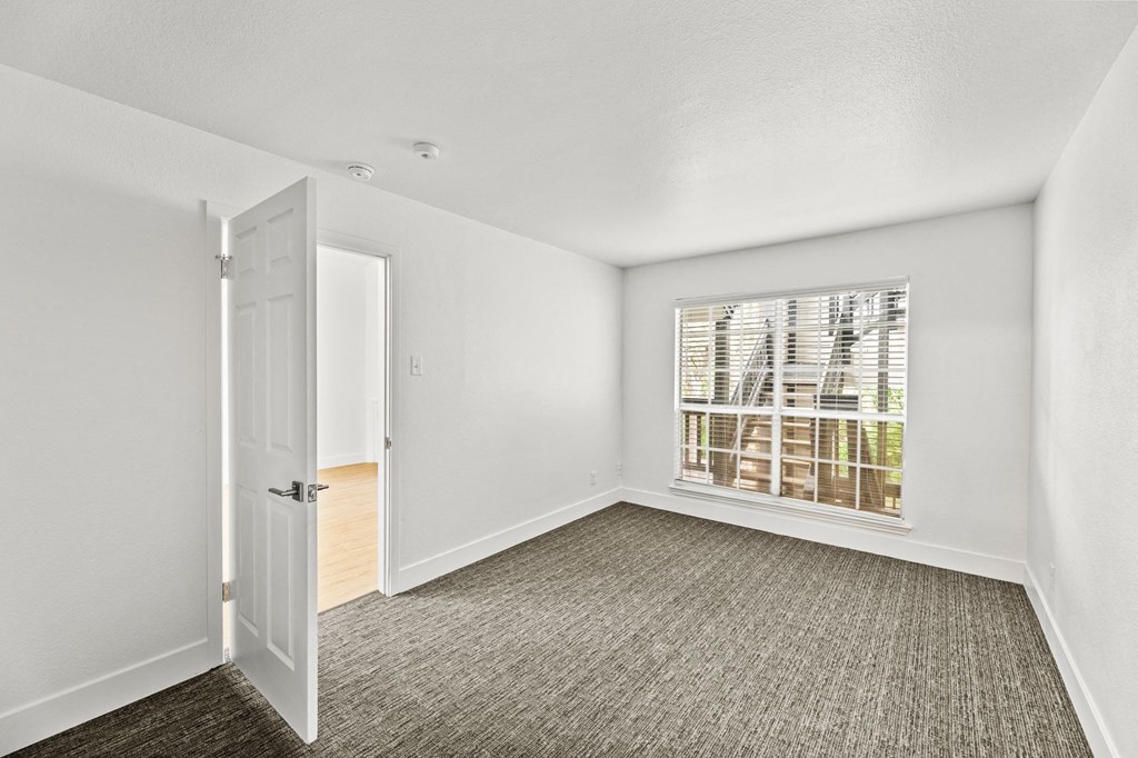 an empty bedroom with a large window and a door to a closet