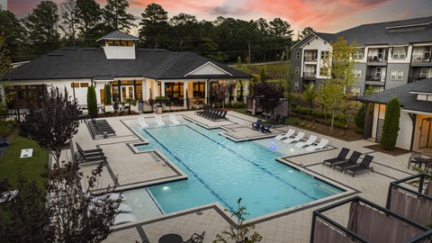 a swimming pool with lounge chairs in front of a house