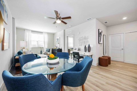 A dining room with a glass table and blue chairs.