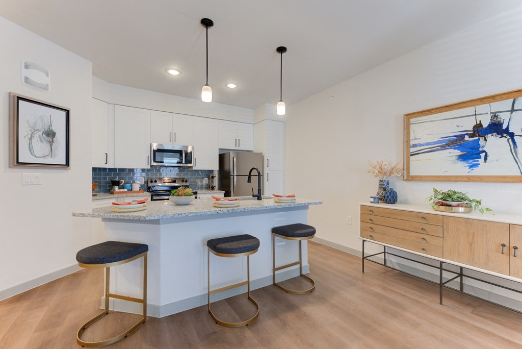 a kitchen with a large island with three stools in front of a counter top