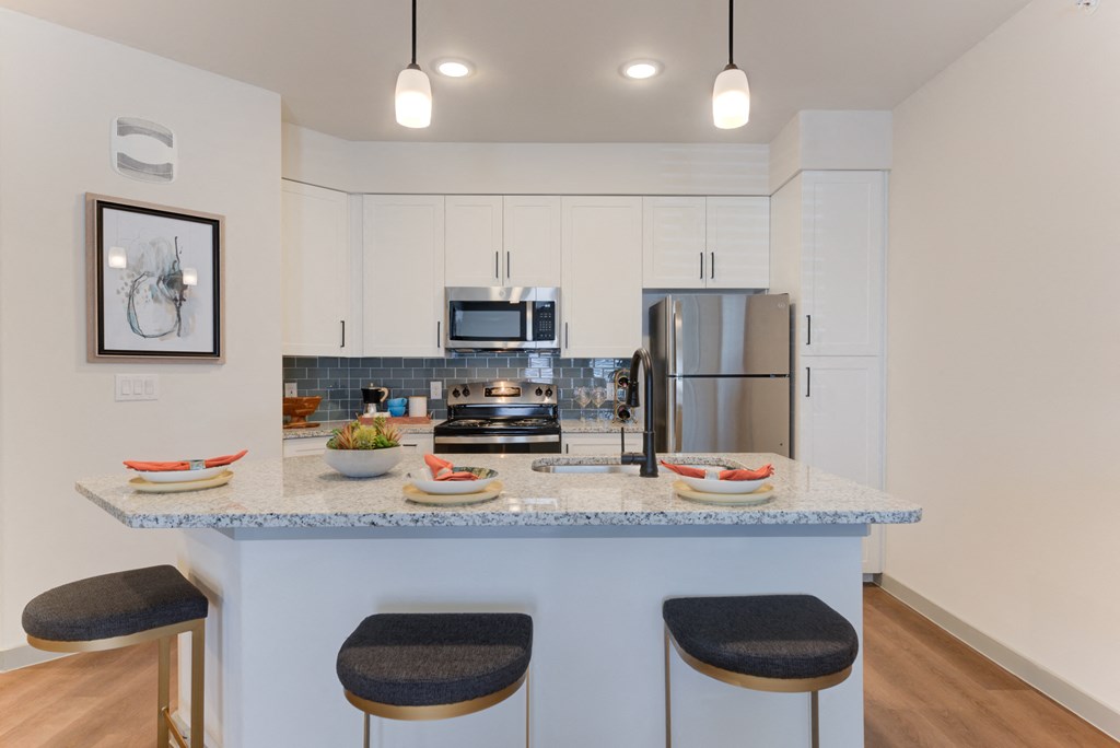 a kitchen with a granite counter top with three stools