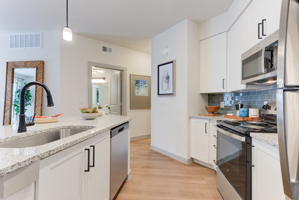 a kitchen with white cabinets and granite counter tops and stainless steel appliances