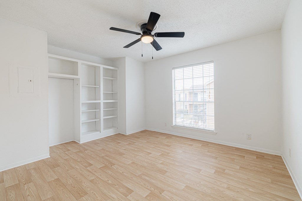 an empty living room with a ceiling fan and a window