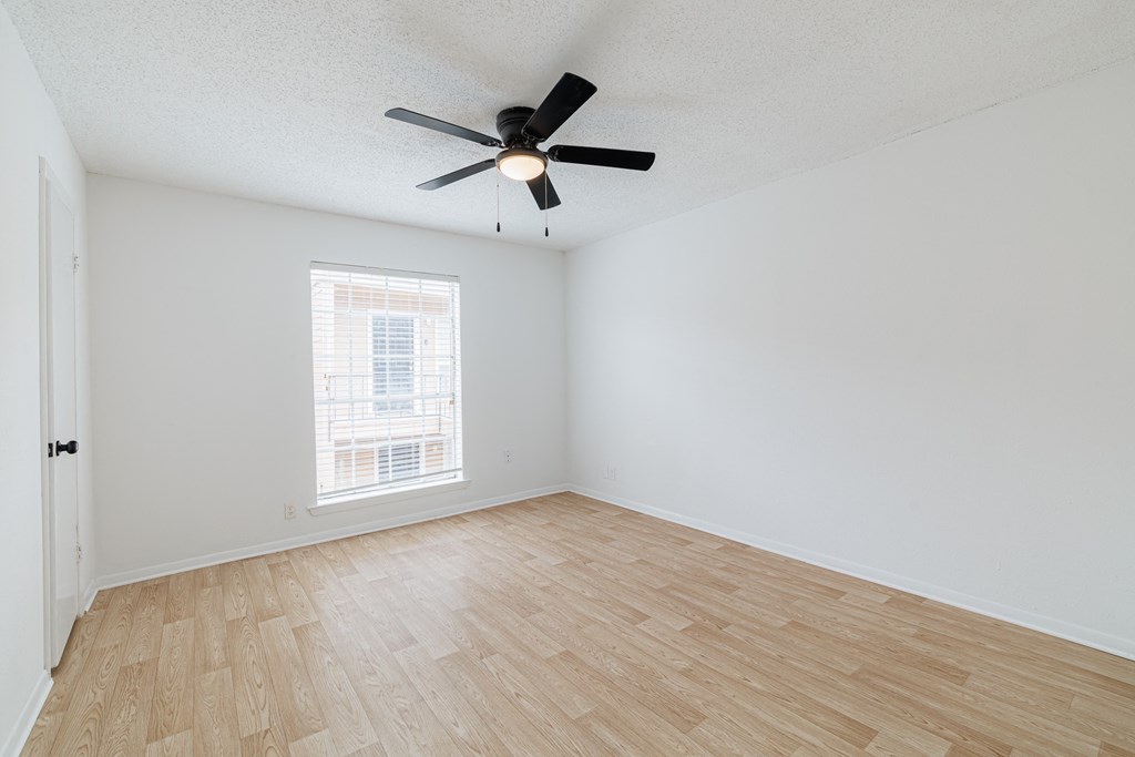 an empty living room with hardwood floors and a ceiling fan