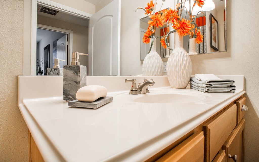 A bathroom sink with a white counter top and a mirror above it.