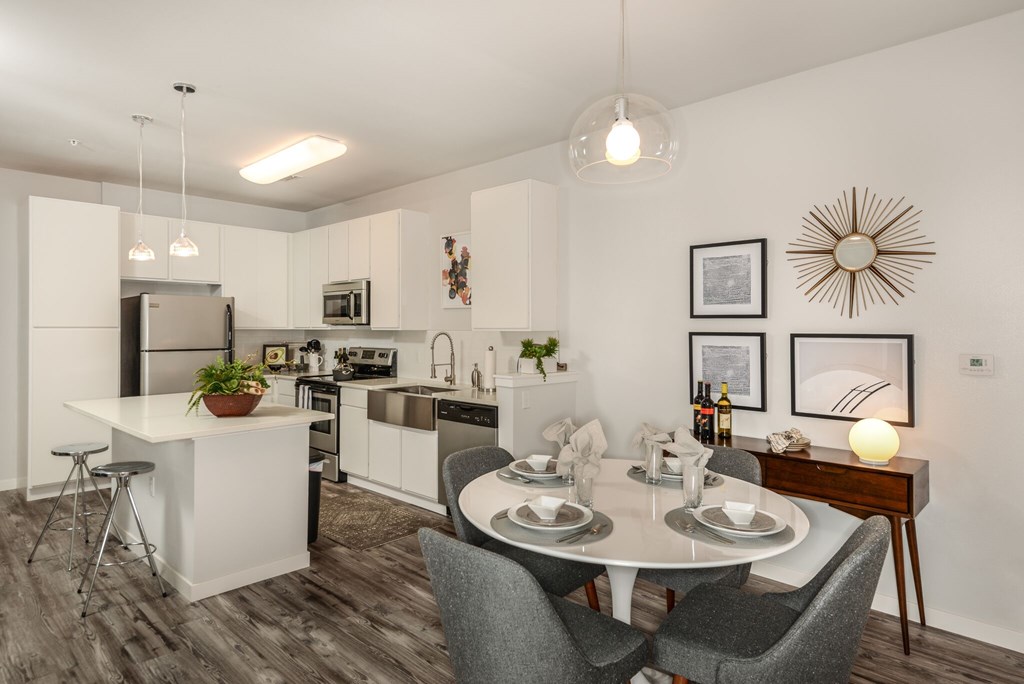 A modern kitchen with a dining table set for two.