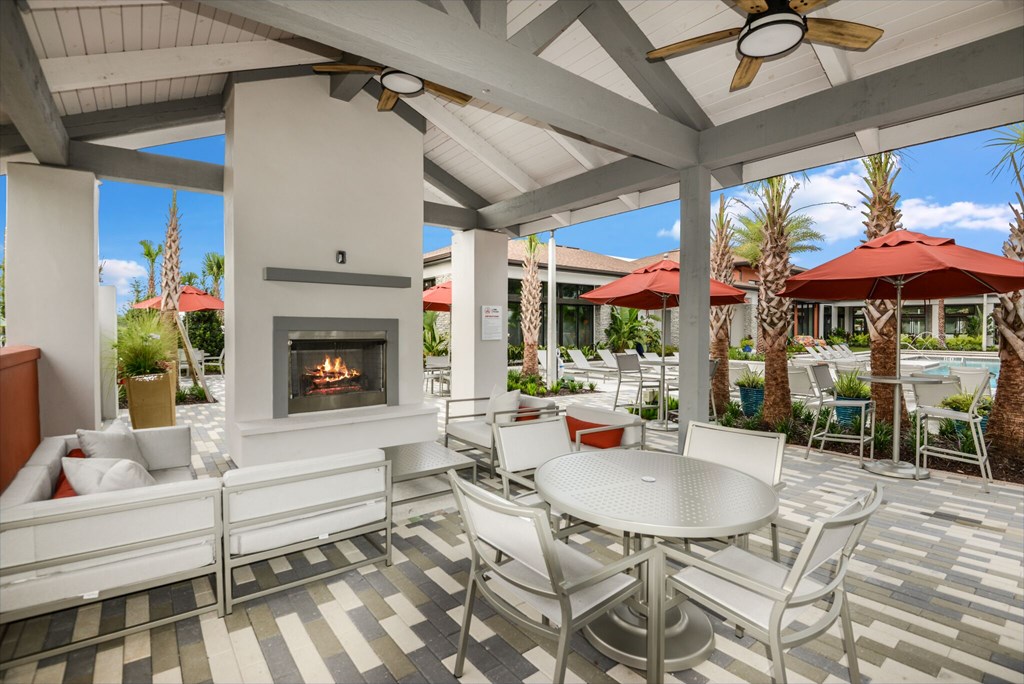 A patio with a fireplace and chairs.