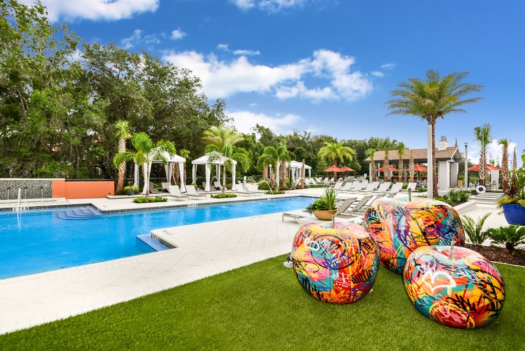 A pool surrounded by palm trees and a white gazebo.