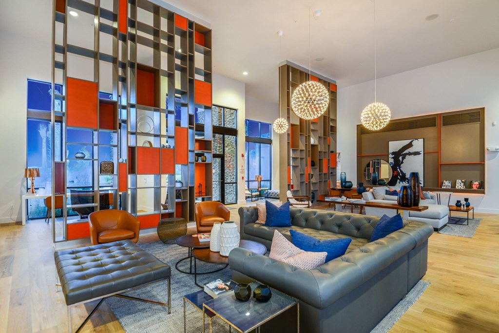 A modern living room with a grey sofa and a glass partition.