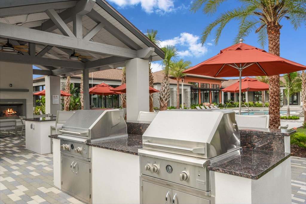 A large outdoor kitchen with a grill and a table.