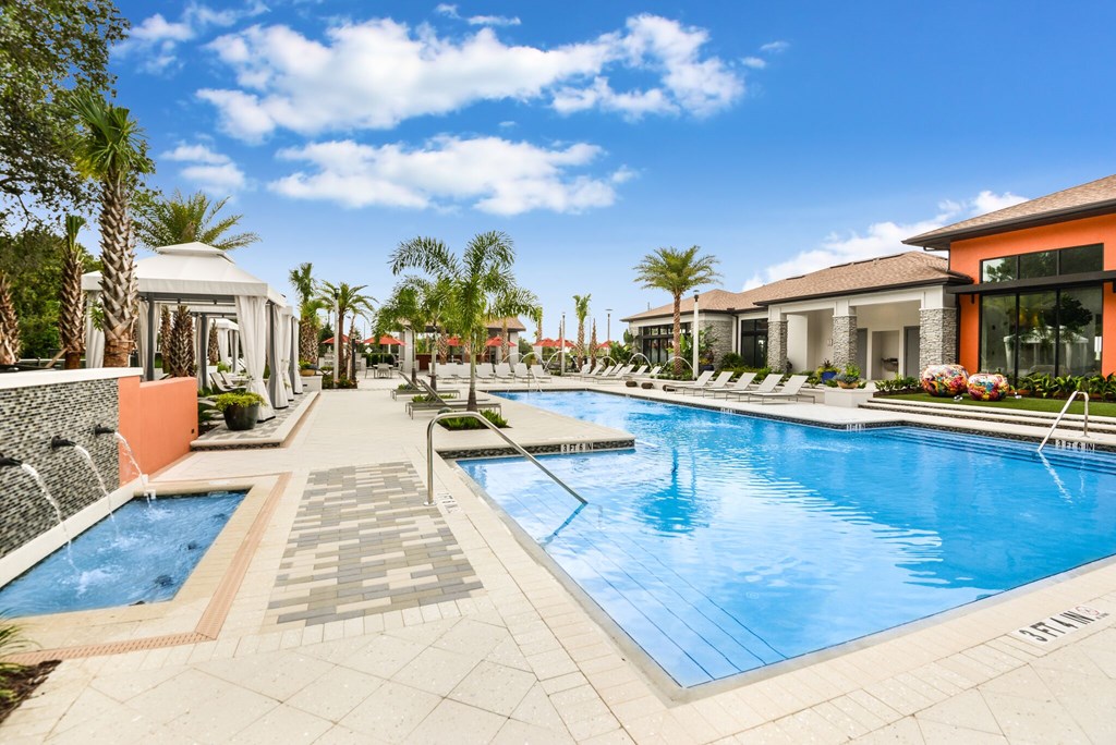 A swimming pool surrounded by a tiled walkway and palm trees.