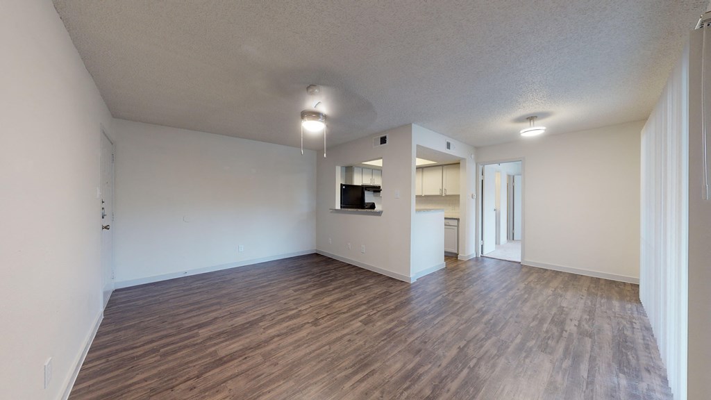 the living room and kitchen of an empty apartment with wood flooring