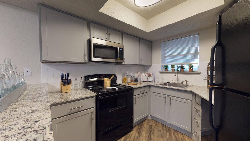 a kitchen with white cabinets and black appliances and granite counter tops