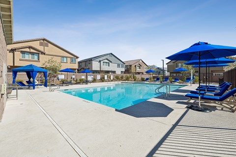 A swimming pool surrounded by blue umbrellas and lounge chairs.