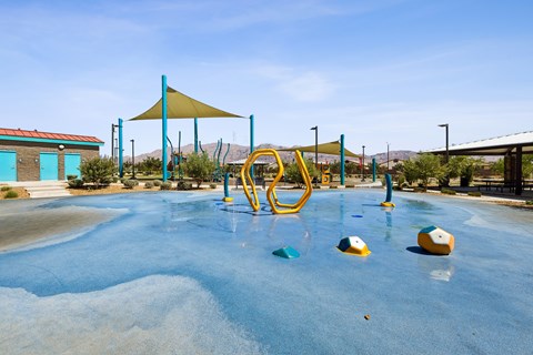 A playground with a blue water feature and yellow and blue play equipment.