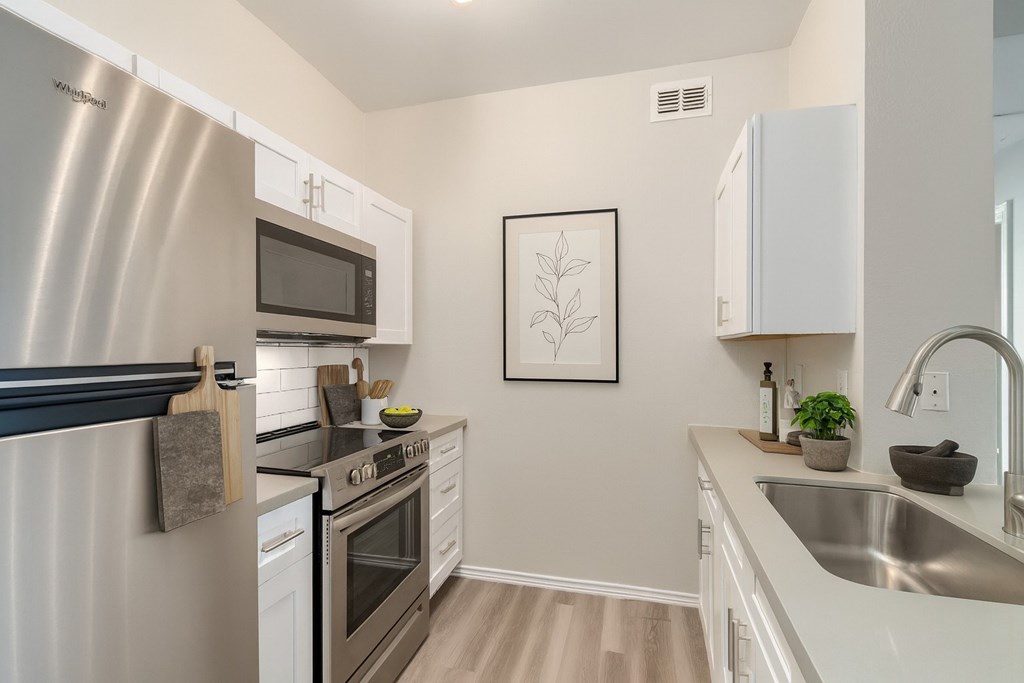 A modern kitchen with a stainless steel refrigerator and white cabinets.