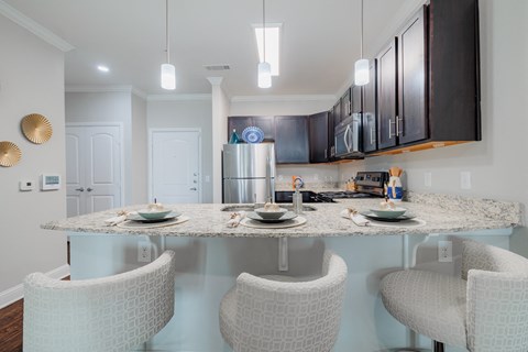 a kitchen with a granite counter top and a bar with three chairs
