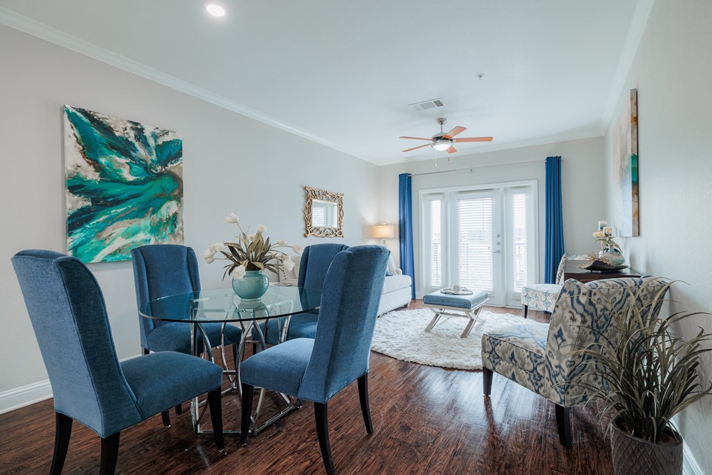 a living room with a glass dining room table with blue chairs