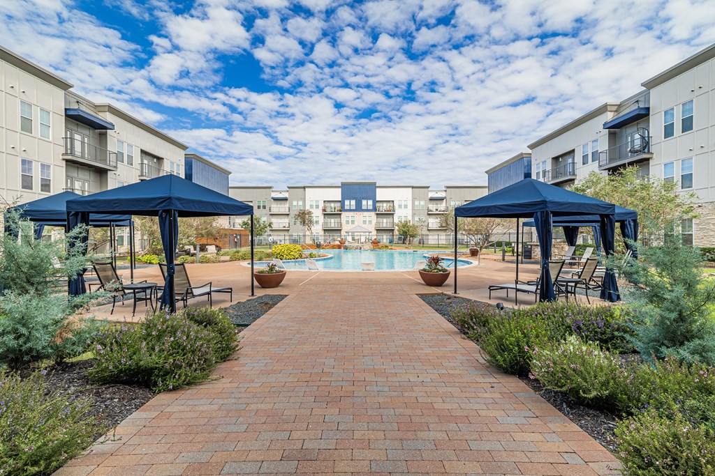 a courtyard with umbrellas and chairs and a swimming pool